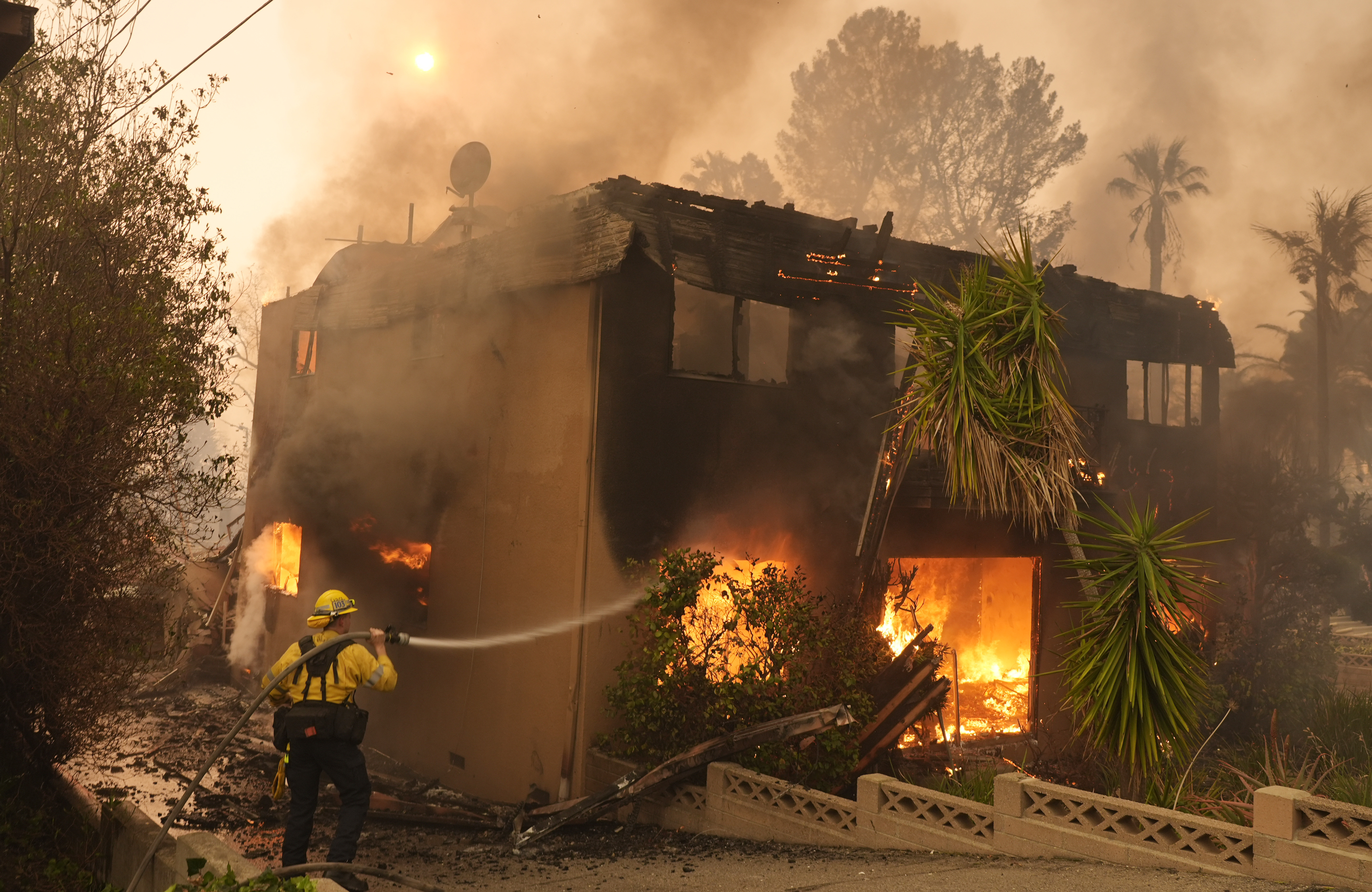 A firefighter tries to extinguish flames at a burning apartment building.