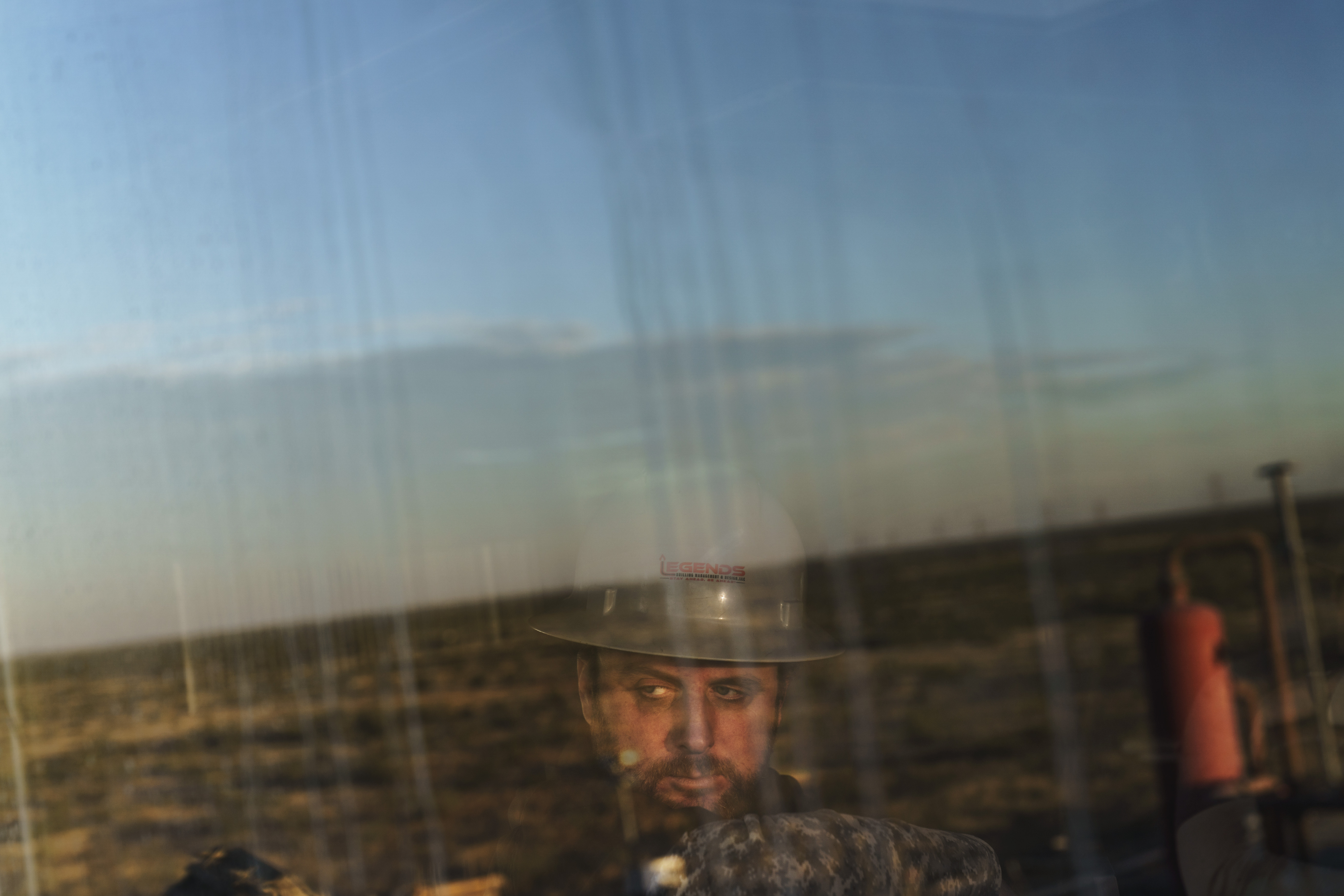 A well site supervisor looks onto the Permian Basin from the control room of an oil drilling rig. A well site supervisor looks onto the Permian Basin from the control room of an oil drilling rig.